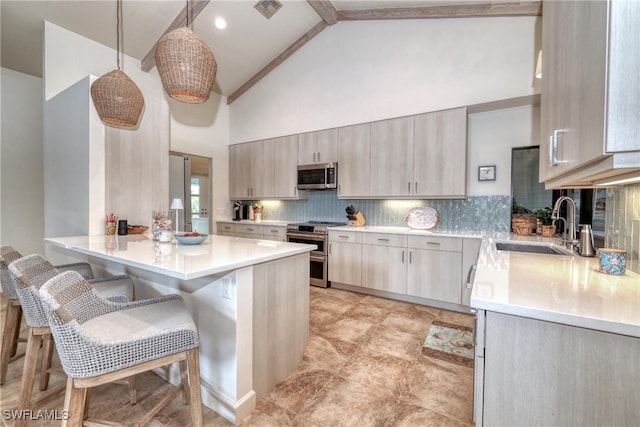 kitchen with a peninsula, a breakfast bar, a sink, appliances with stainless steel finishes, and tasteful backsplash