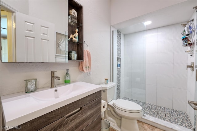 bathroom featuring toilet, a stall shower, and vanity