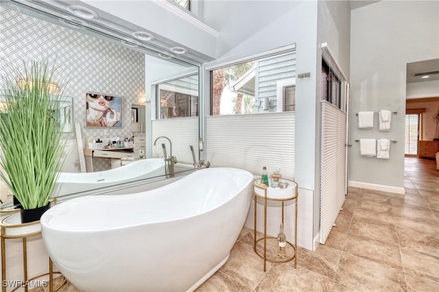 full bath featuring a soaking tub, tile patterned flooring, baseboards, and vaulted ceiling