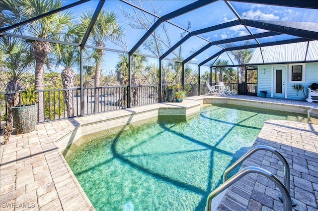 outdoor pool featuring glass enclosure and a patio