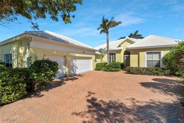 single story home featuring decorative driveway, an attached garage, and stucco siding