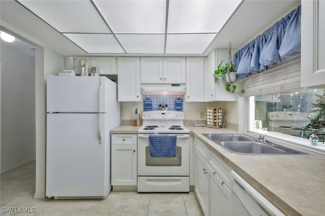 kitchen featuring white appliances, white cabinets, light countertops, under cabinet range hood, and a sink