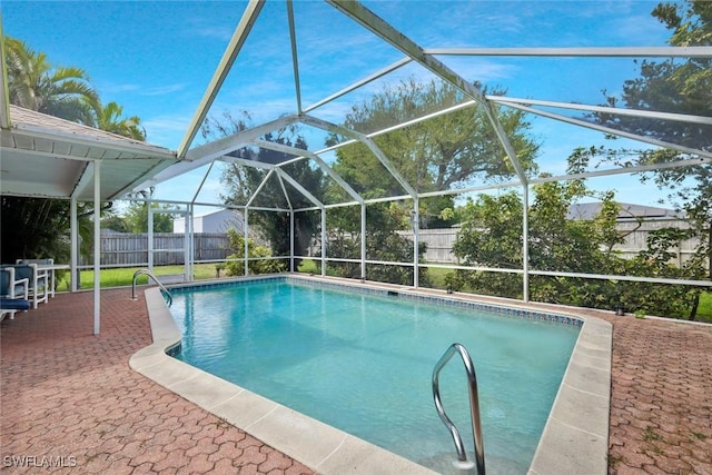 view of swimming pool with glass enclosure, a patio area, a fenced backyard, and a fenced in pool