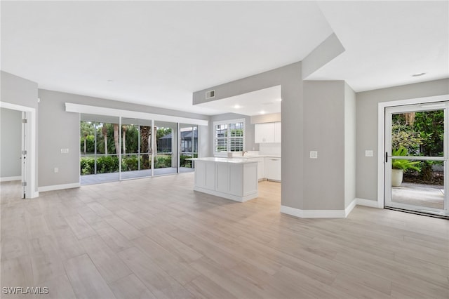 unfurnished living room featuring light wood-style floors, visible vents, and baseboards