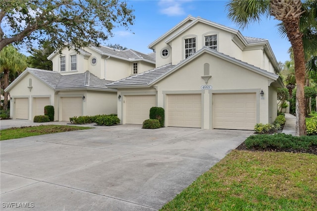 view of front facade featuring driveway, a tiled roof, an attached garage, and stucco siding