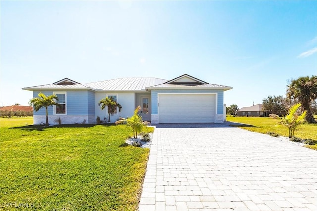 ranch-style house with metal roof, a garage, decorative driveway, a front lawn, and a standing seam roof