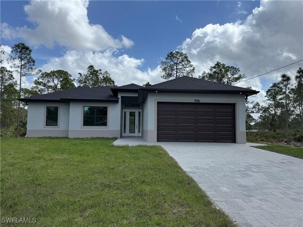 view of front facade with an attached garage, a front lawn, decorative driveway, and stucco siding