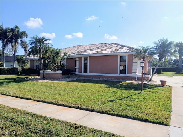 ranch-style house with a tiled roof, a front lawn, and stucco siding