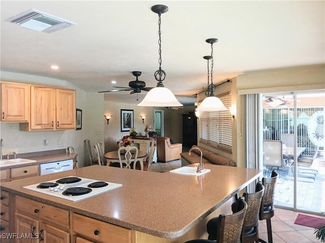 kitchen featuring a center island, visible vents, light brown cabinetry, a sink, and white appliances