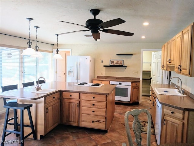 kitchen featuring a kitchen island, white appliances, visible vents, and a sink