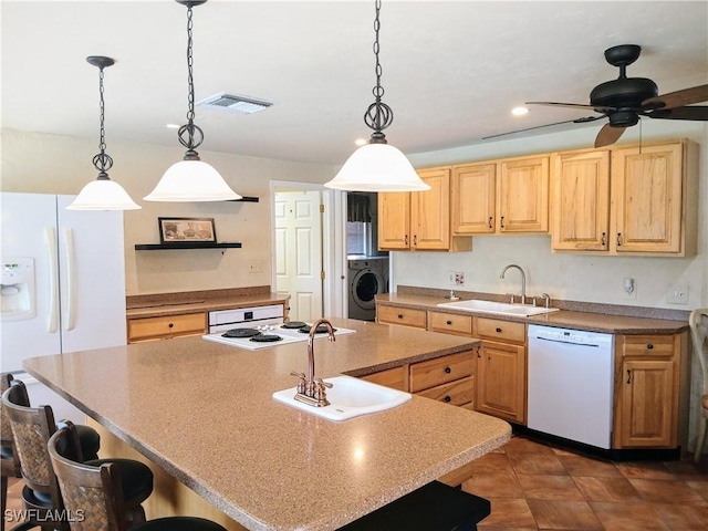 kitchen featuring washer / clothes dryer, visible vents, a sink, white appliances, and a kitchen breakfast bar