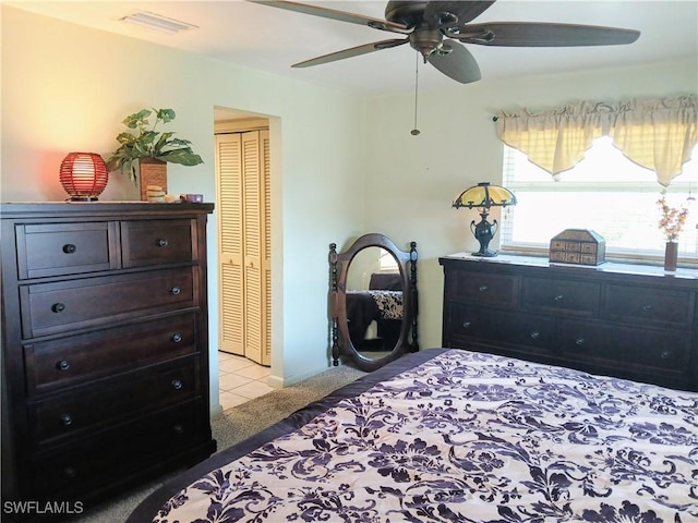 bedroom with ceiling fan, light tile patterned floors, light carpet, visible vents, and a closet