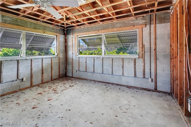 interior space featuring ceiling fan and concrete block wall