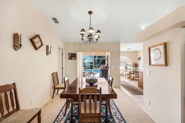 dining area featuring a notable chandelier, visible vents, and light colored carpet