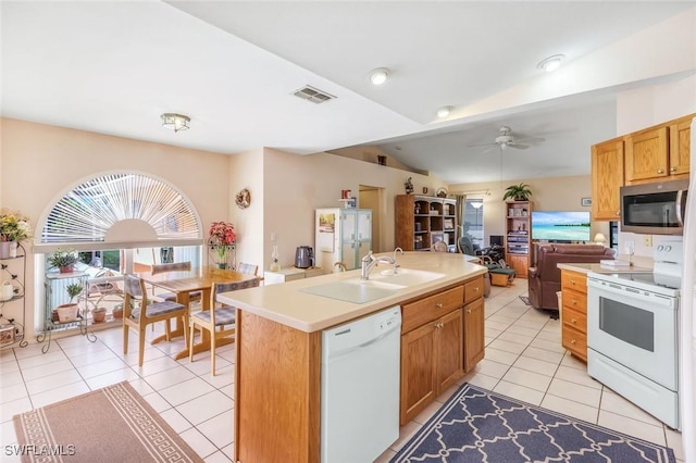 kitchen with visible vents, open floor plan, light tile patterned floors, white appliances, and a sink