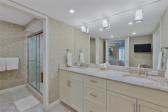 full bath with wallpapered walls, connected bathroom, baseboards, and a sink