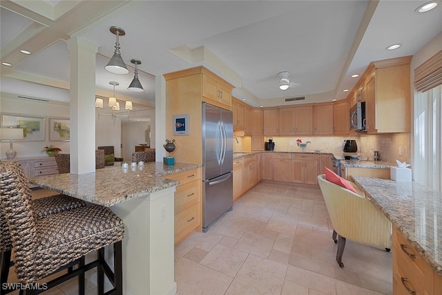 kitchen featuring a breakfast bar area, stainless steel appliances, tasteful backsplash, visible vents, and light brown cabinets