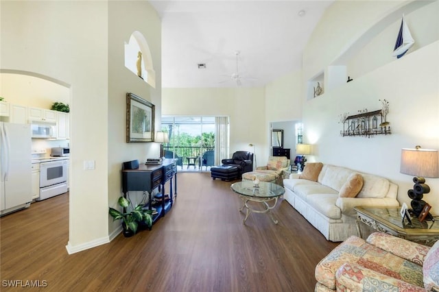 living room featuring arched walkways, visible vents, a high ceiling, a ceiling fan, and wood finished floors