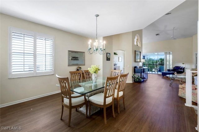 dining room featuring arched walkways, a notable chandelier, wood finished floors, baseboards, and vaulted ceiling