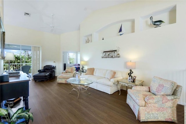 living room featuring ceiling fan, a high ceiling, visible vents, and wood finished floors