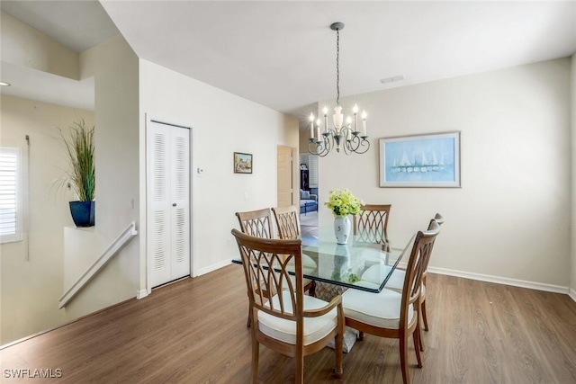 dining room with baseboards, visible vents, a chandelier, and wood finished floors