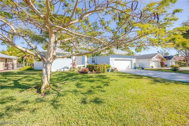 view of front facade featuring an attached garage, fence, driveway, and a front lawn