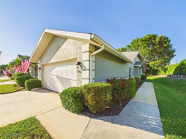 view of home's exterior featuring an attached garage, driveway, a lawn, and stucco siding