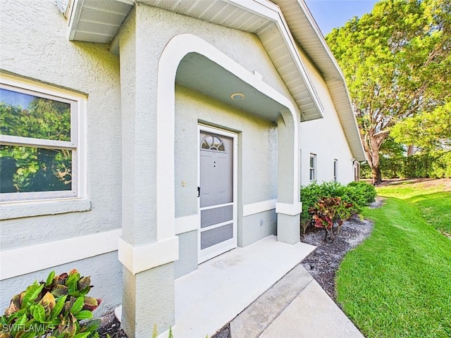 doorway to property featuring a yard and stucco siding