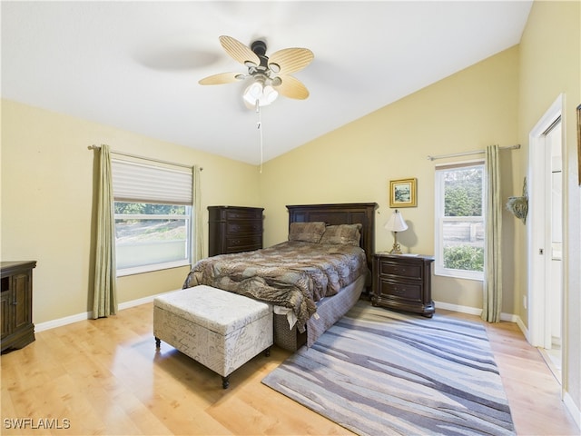 bedroom featuring baseboards, vaulted ceiling, multiple windows, and light wood-style floors