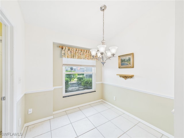 tiled empty room with baseboards, a chandelier, and vaulted ceiling