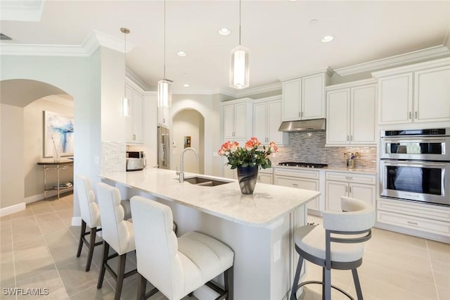 16445 Carrara Way Unit 201, Naples, FL 34110 - kitchen featuring a sink, arched walkways, gas stovetop, double oven, and ornamental molding