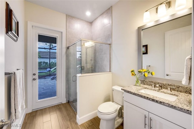 full bath featuring a stall shower, vanity, toilet, and wood finished floors