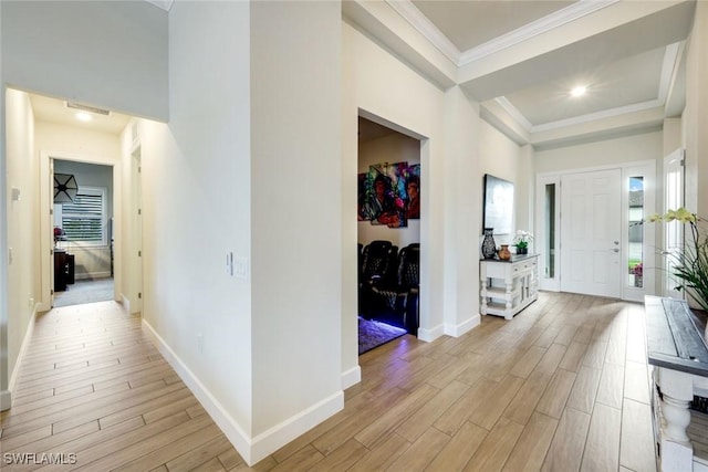 foyer featuring light wood-style floors, a tray ceiling, ornamental molding, and baseboards