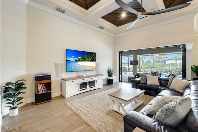 living room featuring light wood finished floors, visible vents, a high ceiling, coffered ceiling, and baseboards