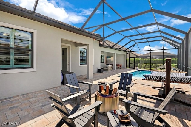 pool with a lanai, a patio area, and a fire pit