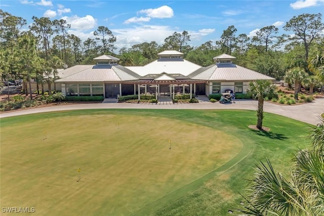 9151 Snowy Owl Way, Naples, FL 34120 - view of front of house with a standing seam roof, curved driveway, view of golf course, and metal roof