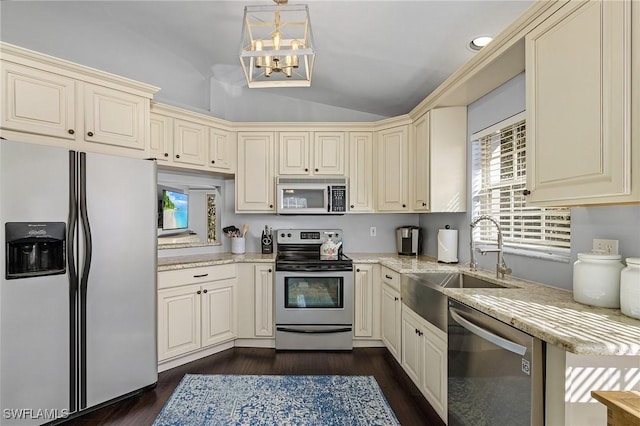 kitchen featuring dark wood finished floors, appliances with stainless steel finishes, vaulted ceiling, cream cabinetry, and a sink