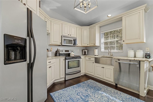 kitchen with appliances with stainless steel finishes, dark wood-style flooring, a sink, and cream cabinets