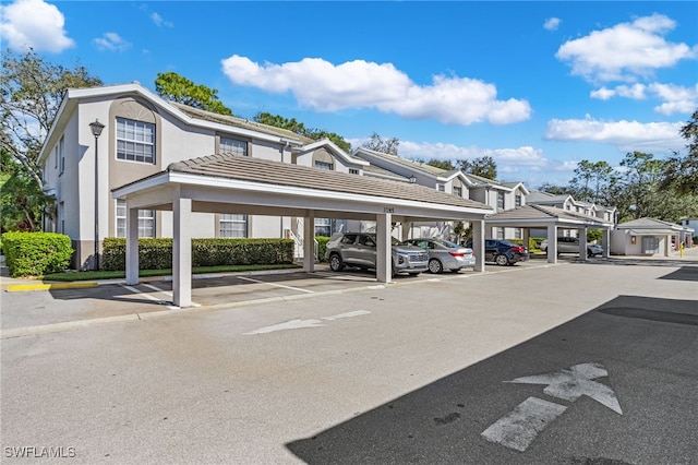 view of building exterior with covered and uncovered parking