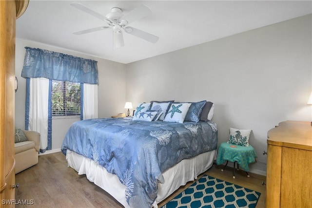 bedroom featuring ceiling fan, baseboards, and wood finished floors