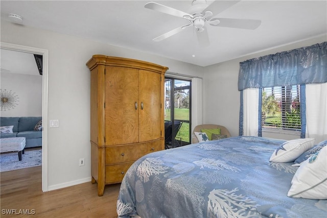 bedroom featuring access to exterior, multiple windows, baseboards, and wood finished floors