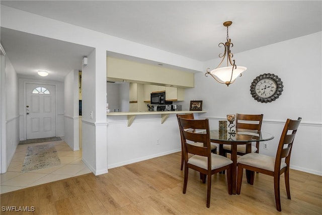 dining space with light wood-type flooring and baseboards