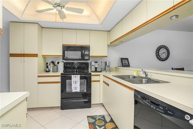 kitchen with black appliances, cream cabinetry, a sink, and light countertops