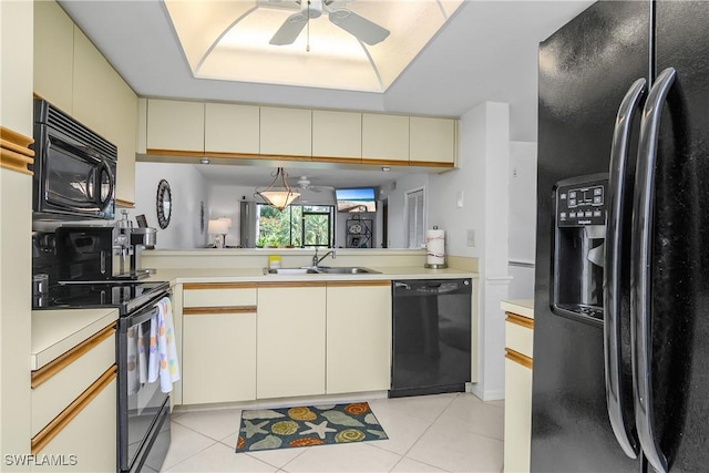 kitchen with light tile patterned floors, cream cabinets, light countertops, black appliances, and a sink