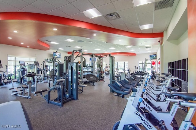 workout area featuring visible vents, a drop ceiling, and a wealth of natural light