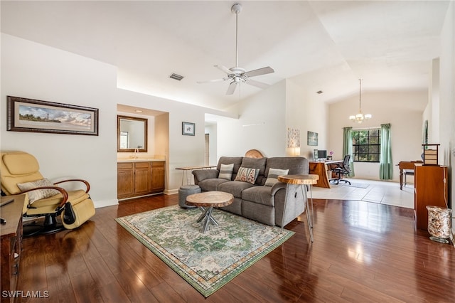 living room featuring high vaulted ceiling, ceiling fan with notable chandelier, dark wood-style flooring, visible vents, and baseboards