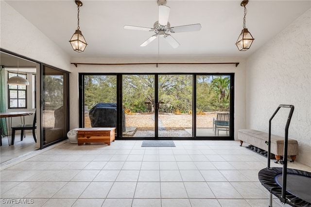 unfurnished sunroom with lofted ceiling, ceiling fan, and plenty of natural light