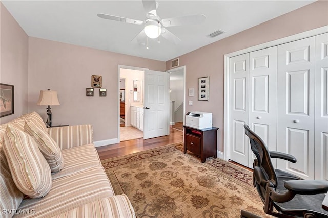 office space featuring a ceiling fan, wood finished floors, visible vents, and baseboards