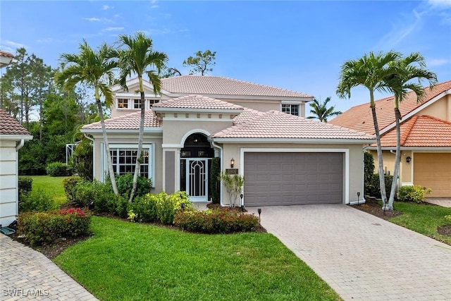 mediterranean / spanish home with a garage, a tiled roof, a front lawn, and stucco siding