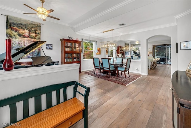 dining area with visible vents, arched walkways, hardwood / wood-style flooring, ornamental molding, and ceiling fan with notable chandelier